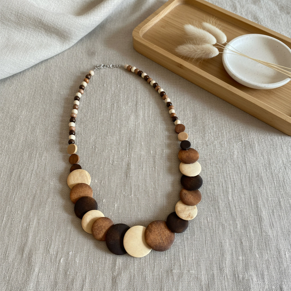 Collier long en bois naturel avec perles rondes et disques superposés aux tons beige et brun, bijou bohème élégant